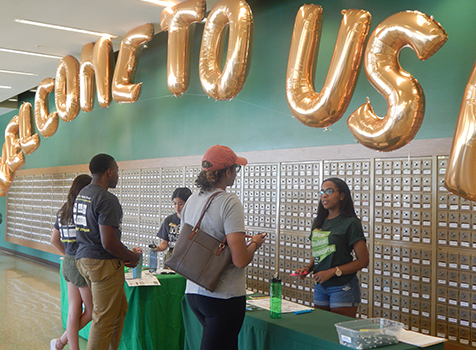 Two students standing behind a table underneath a "Welcome to USF" banner assist students