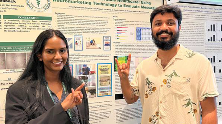 Two students posing in front of research posters