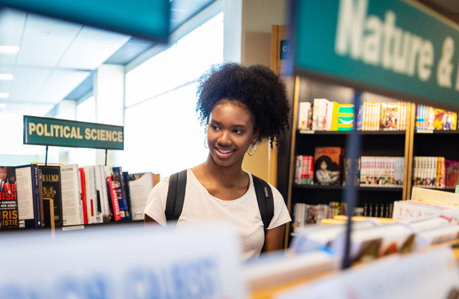 Young woman browsing bookshelves at Tampa campus bookstore