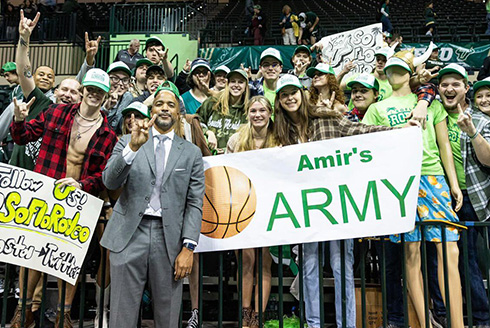 Coach Amir stands among a sea of fans, a sign reads Amir's Army
